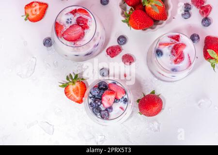 Sommermilchbeere alkoholfreier Cocktail, süße vegane Kokosmilch milchfreier Mocktail, mit frischen Erdbeeren, Heidelbeeren, Himbeeren und zerstoßenem Eis, auf B. Stockfoto
