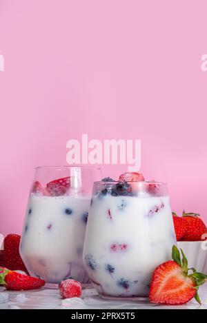 Sommermilchbeere alkoholfreier Cocktail, süße vegane Kokosmilch milchfreier Mocktail, mit frischen Erdbeeren, Heidelbeeren, Himbeeren und zerstoßenem Eis, auf B. Stockfoto