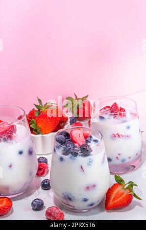Sommermilchbeere alkoholfreier Cocktail, süße vegane Kokosmilch milchfreier Mocktail, mit frischen Erdbeeren, Heidelbeeren, Himbeeren und zerstoßenem Eis, auf B. Stockfoto