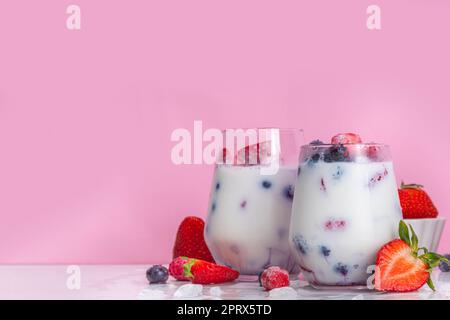 Sommermilchbeere alkoholfreier Cocktail, süße vegane Kokosmilch milchfreier Mocktail, mit frischen Erdbeeren, Heidelbeeren, Himbeeren und zerstoßenem Eis, auf B. Stockfoto
