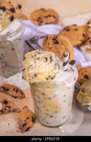 Essbarer roher Keksteig-Smoothie. Süßes, rohes keksteig-Shake-Getränk mit Schokoladenkeksen auf beigefarbenem Hintergrund Stockfoto