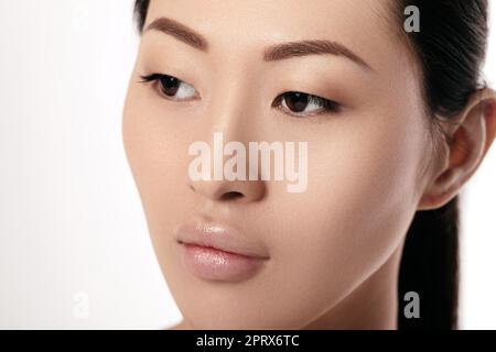 Close-up Portrait von schöne junge Asiatin auf weißem Hintergrund closeup. Mädchen mit sauberen Haut. Weibliche Lippen nach augmentation Verfahren Stockfoto