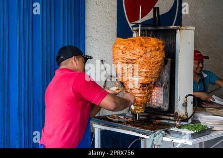 In Tlacolula de Matamoros, Central Valley, Oaxaca, Mexiko, schneidet man gegrilltes Schweinefleisch aus einem Trompo. Stockfoto