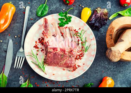 Leckere rohe Lammrippchen und Gewürze auf dem Küchentisch. Stockfoto