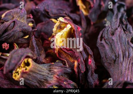 Leuchtend rosafarbener getrockneter Hibiskus-Tee hinterlässt einen strukturierten Hintergrund aus nächster Nähe. Stockfoto