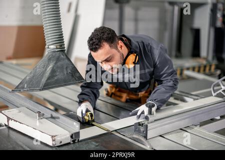 Holzwender messen und berechnen die richtige Größe des Werkstücks mit Hand- und Elektrowerkzeugen. Schneiden, Formen, Drehen, Glätten und Ausbalancieren von Holzbefestigungen Stockfoto