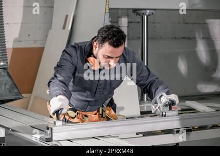 Holzwender messen und berechnen die richtige Größe des Werkstücks mit Hand- und Elektrowerkzeugen. Schneiden, Formen, Drehen, Glätten und Ausbalancieren von Holzbefestigungen Stockfoto