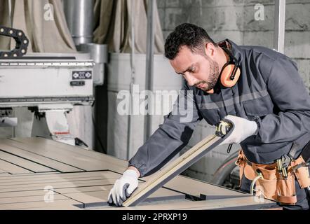 Holzwender messen und berechnen die richtige Größe des Werkstücks mit Hand- und Elektrowerkzeugen. Schneiden, Formen, Drehen, Glätten und Ausbalancieren von Holzbefestigungen Stockfoto