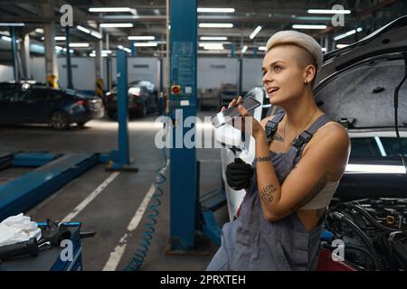 Junge Frau steht unter Autos in der Autoherstellung Stockfoto