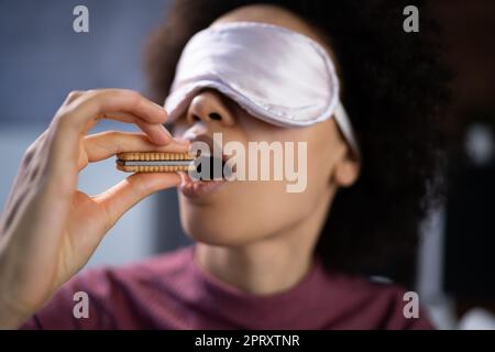 Porträt der jungen Frau mit verbundenen Augen Prüfen von Essen Stockfoto