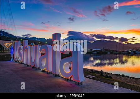 Ushuaia schreibt an der Grenze zur Bucht bei Sonnenuntergang Stockfoto