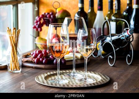 Drei Sorten Wein auf einem Metalltablett mit einer Wurstplatte dahinter. Stockfoto