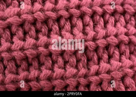 Rosafarbenes, handgefertigtes Strickmaterial mit Textilhintergrund. Stockfoto