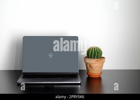 Laptop-Modell auf schwarzem Tisch mit Pflanze Stockfoto