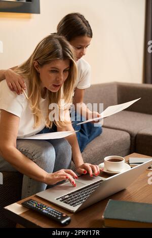 Die kleine Tochter hilft ihrer Mutter, zu Hause zu arbeiten Stockfoto