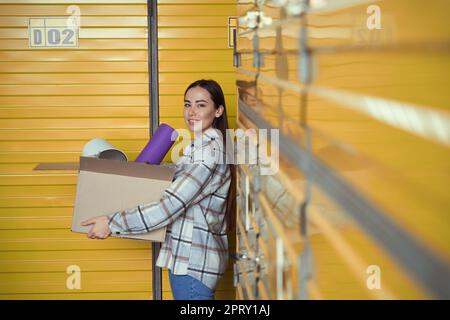Hübsche junge Frau, die eine Schachtel voller Sachen hat Stockfoto