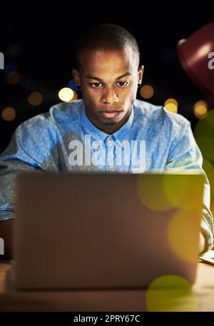 Darauf fokussiert, es zu erledigen. Ein gutaussehender junger Mann, der nachts mit seinem Laptop arbeitet Stockfoto