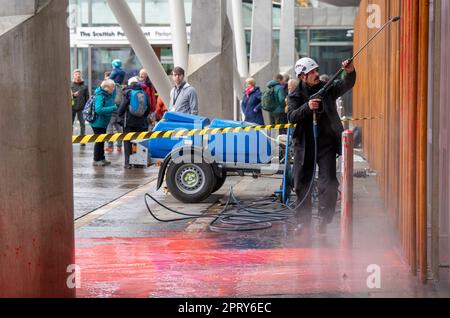 Arbeiter säubern rote Farbe, die von Klimaschutzaktivisten vor dem Schottischen Parlament in Edinburgh geworfen wurde. Foto: Donnerstag, 27. April 2023. Stockfoto