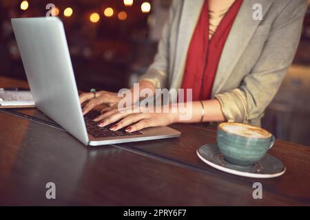 Die perfekte Arbeitsumgebung, um produktiv zu bleiben. Eine nicht identifizierbare Frau, die an einem Laptop in einem Café arbeitet Stockfoto