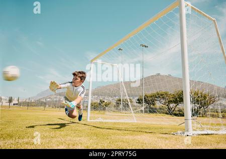 Fußball, Sport und Kinder, bei denen ein Torwart während eines Wettkampfspiels auf einem Rasen- oder Spielfeld einen Schuss spart. Fußball, Kinder und Tor mit einem männlichen C. Stockfoto