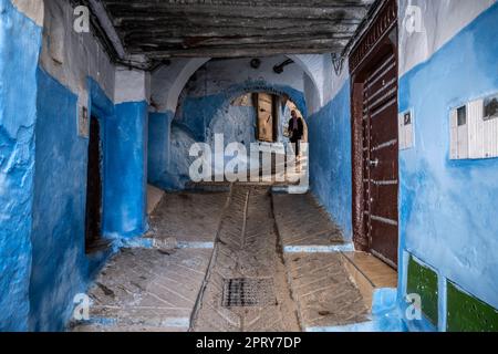 Eine Frau, die die Treppe einer steilen Gasse in der Medina von Tetouan hinuntergeht. Stockfoto