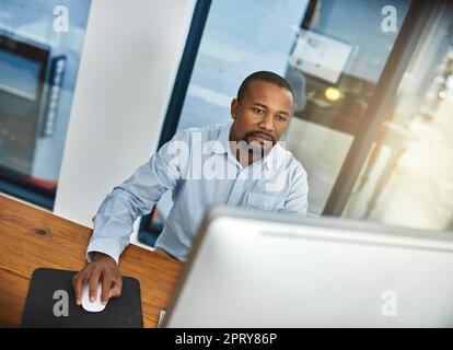 HES ist der Frist gewidmet. Ein Geschäftsmann, der im Büro an seinem Computer arbeitet Stockfoto