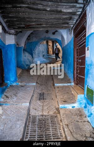 Ein Mann, der die Treppe einer steilen Gasse in der Medina von Tetouan hinuntergeht. Stockfoto