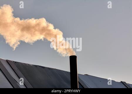 Rauch kommt aus dem Kamin der Bourgeoisie. Der Herd wird erhitzt. Hochwertiges Foto Stockfoto