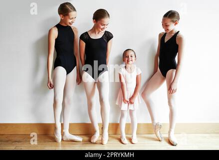 Ballerina-Superstar in der Entwicklung. Eine Gruppe junger Ballerinas, die ein kleines Mädchen Ballett in einem Tanzstudio unterrichten. Stockfoto