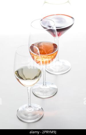 Drei Gläser verschiedener Weine hintereinander auf weißem Hintergrund. Stockfoto