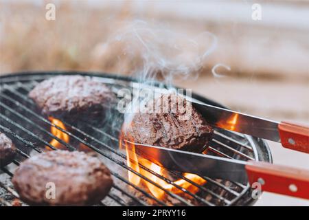 Nahaufnahme Foto von einem leckeren saftigen Patty für Burger auf Grill auf offenem Feuer gekocht. Traditionelles Köstliches Essen. USA Independence Day. Familienfest Im Freien Stockfoto