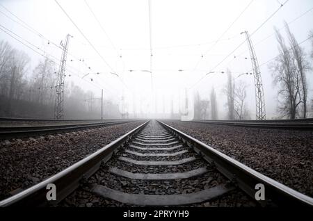 Die Bahngleise an einem nebligen Morgen. Viele Schienen und Schläfer gehen in den nebligen Horizont. Fischaugenfoto mit erhöhter Verzerrung Stockfoto