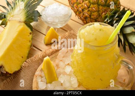 Details von frisch zubereiteter Ananascreme mit Obst auf einem Holztisch. Erhöhte Aussicht. Horizontale Zusammensetzung. Stockfoto