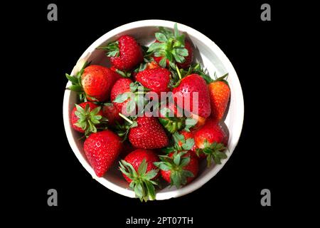 Nahaufnahme einer Schüssel frischer Erdbeeren, isoliert vor schwarzem Hintergrund Stockfoto