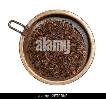 Gebraute, nasse Teeblätter in einem Metallsieb, isoliert vor weißem Hintergrund Stockfoto