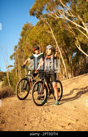 Bis dahin sind wir dran. Eine Frau, die auf etwas zeigte, während sie mit ihrem Freund eine Fahrradtour machte Stockfoto