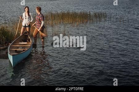 Was gibt es Besseres als Kanufahren? Ein junges Paar, das eine Kanufahrt auf dem See macht. Stockfoto