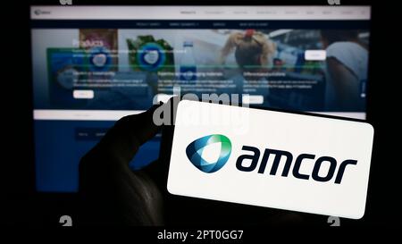 Person, die ein Smartphone mit dem Logo des Verpackungsunternehmens Amcor plc auf dem Bildschirm vor der Website hält. Konzentrieren Sie sich auf das Display des Telefons. Stockfoto