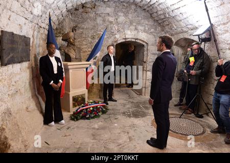 Der französische Präsident Emmanuel Macron würdigt vor einer Statue von Toussaint Louverture, dem Führer der haitianischen Unabhängigkeitsbewegung, bevor er das Chateau de Joux anlässlich einer Zeremonie anlässlich des 175. Jahrestages der Abschaffung der Sklaverei in Frankreich, in La Cluze-et-Mijoux, nahe Besancon, Ostfrankreich, am 27. April besucht; 2023. Macron besuchte das Chateau de Joux, um den 220. Todestag des französisch-haitianischen Generals Toussaint Louverture an dem Ort zu würdigen, an dem er bis zu seinem Tod inhaftiert war. Foto: Raphael Lafargue/ABACAPRESS.COM Stockfoto