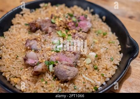 Rindfleisch mit gebratenem Knoblauchreis, ein japanisches Gericht bestehend aus einer Schüssel Reis garniert mit seltenem Rindfleisch, serviert auf einer schwarzen Pfanne Stockfoto