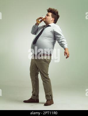 Es ist so gut, wenn es auf die Lippen trifft. Ein übergewichtiger Mann, der ein Pint Bier abwirft Stockfoto