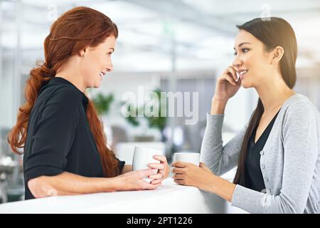 Es ist wichtig, am Arbeitsplatz auszukommen. Zwei Geschäftsfrauen, die ein freundliches Gespräch im Büro führen Stockfoto