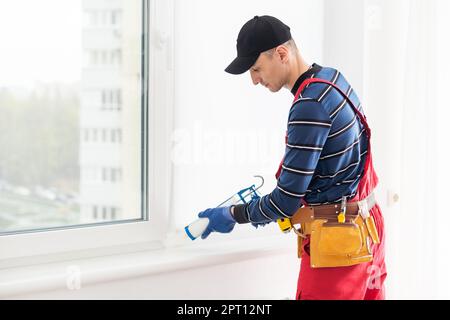 Versiegelung des Fensters durch den Bauarbeiter mit Abdichtung, Verschließung Stockfoto