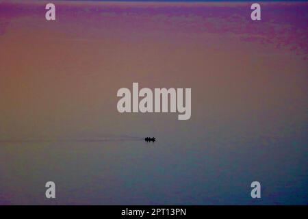 Einsames Boot weit draußen auf dem Eriesee während der blauen Stunde nach Sonnenuntergang Stockfoto