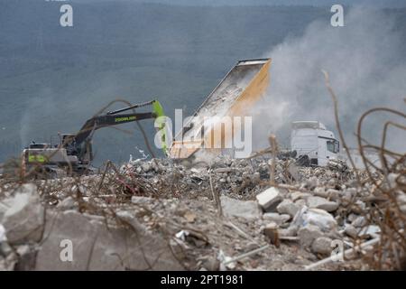 Antakya, Türkei. 27. April 2023. Bagger sind damit beschäftigt, die Trümmer zerstörter Häuser, die auf einem riesigen Gebiet am Stadtrand von Antakya abgeladen wurden, auszugleichen (Luftaufnahme durch eine Drohne). Große Teile der Stadt wurden durch das Erdbeben am 6. Februar vollständig zerstört. Kredit: Boris Roessler/dpa/Alamy Live News Stockfoto