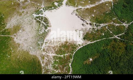 Grüne Pflanzen bedecken die Hänge der Sanddünen im Sommer in Irland, Draufsicht. Wunderschöne irische Hügel, Landschaft. Stockfoto