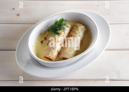 Dünne Pfannkuchen mit Füllung im Ofen gebacken mit geschmolzenem Käse Stockfoto