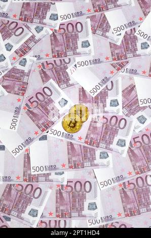 Bitcoins auf einem Stapel 500-Euro-Banknoten. Traditionelles Geld versus Kryptowährungskonzept. Goldmünze über 500-Euro-Scheine. Schließen Stockfoto