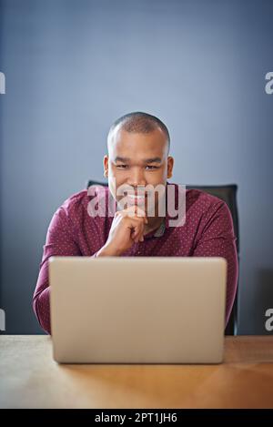 Er hat einen engagierten Mitarbeiter. Ein Geschäftsmann, der an seinem Schreibtisch an seinem Laptop arbeitet Stockfoto