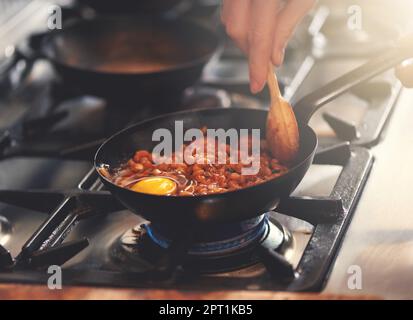 Das Frühstück der Champions. Ein leckeres Gericht aus Bohnen und Eiern, das in einer Pfanne kocht Stockfoto